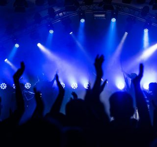 Dynamic concert scene with cheering crowd and vibrant blue lighting.